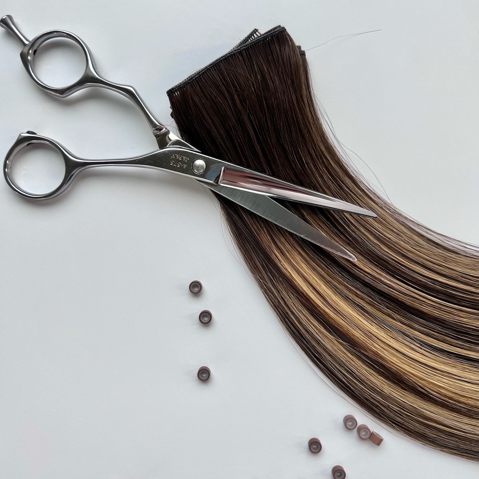 Cristina color Siren Hair Extensions featuring a neutral/warm Level 6 base with piano-keyed dimensional ends, including Level 6 lowlights and Level 10 sunny golden blonde highlights. Perfect for darker &