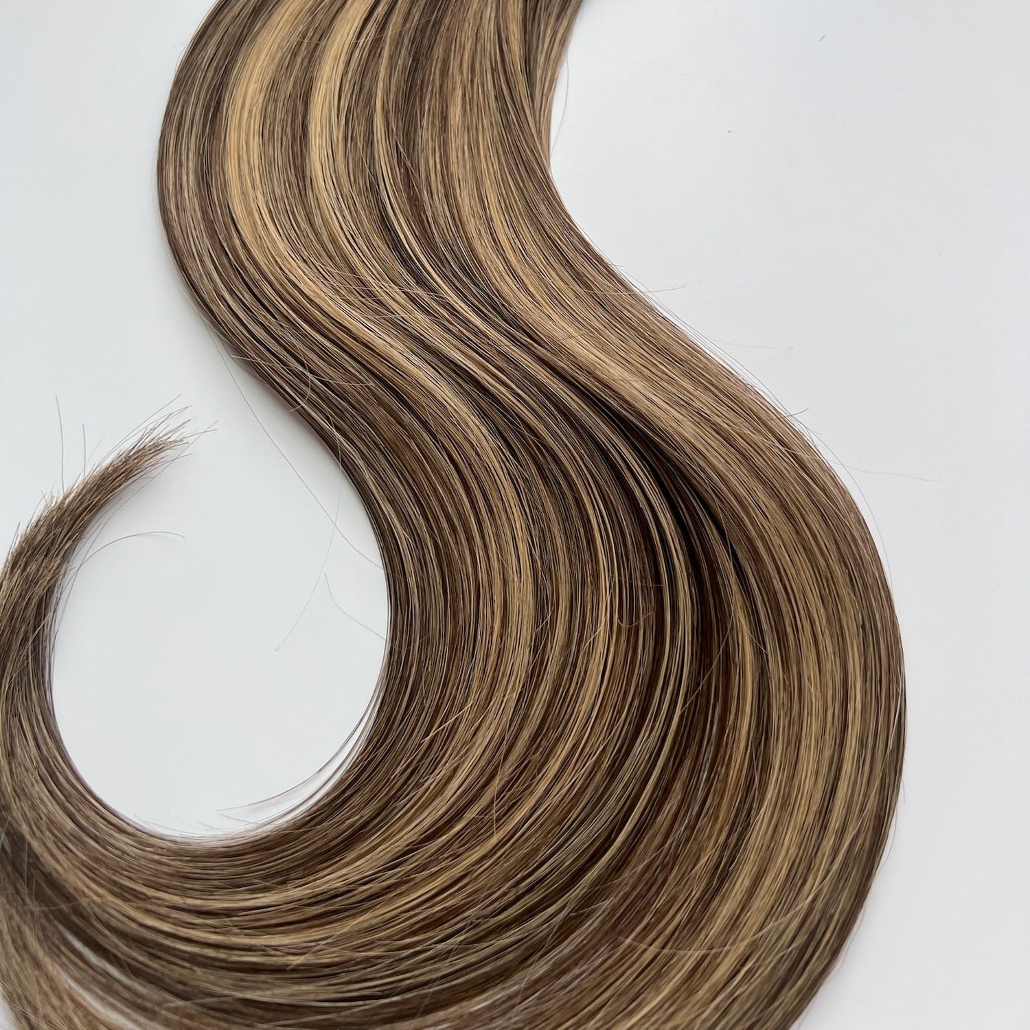 Cristina color Siren Hair Extensions featuring a neutral/warm Level 6 base with piano-keyed dimensional ends, including Level 6 lowlights and Level 10 sunny golden blonde highlights. Perfect for darker &