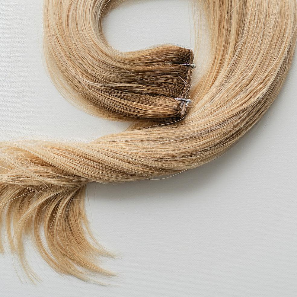 Kayla color Siren Hair Extensions featuring a warm Level 7 base with piano-keyed dimensional ends, including Level 9 sunny golden blonde lowlights and Level 10 sunny golden blonde highlights. Perfect for creating a lived-in sunny blonde look.